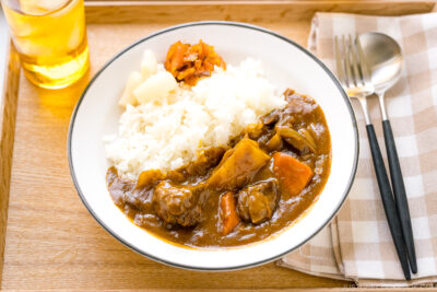 A Japanese plate containing steamed rice and Japanese beef curry garnished with pickles.