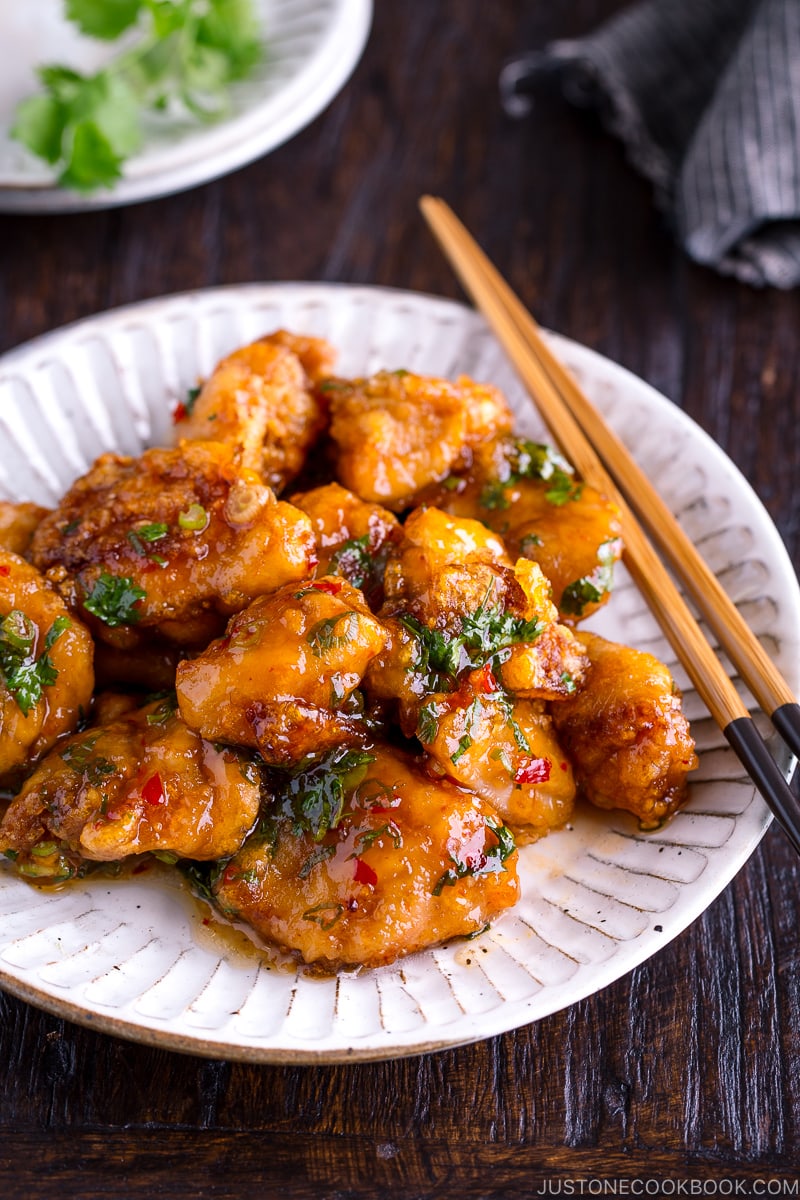 A white plate containing Chicken Karaage with Sweet Chili Sauce and cilantro garnish.