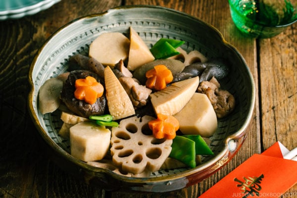 A Japanese ceramic bowl containing simmered chicken and vegetables.