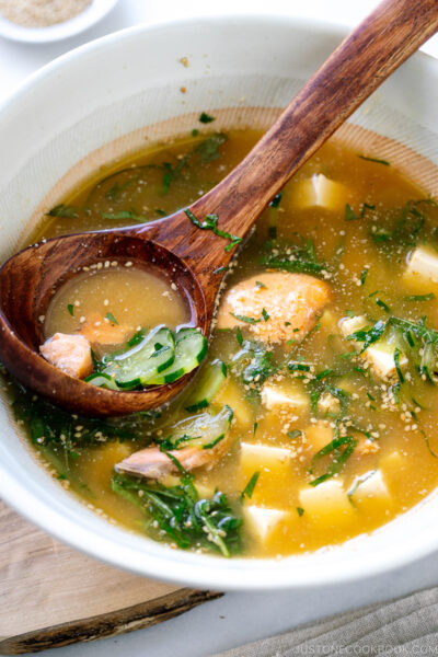 A white Japanese bowl containing cold miso soup (hiyajiru) with tofu, cucumber, and salmon).