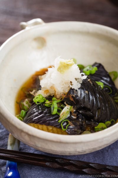 A white ceramic bowl containing eggplant agebitashi.