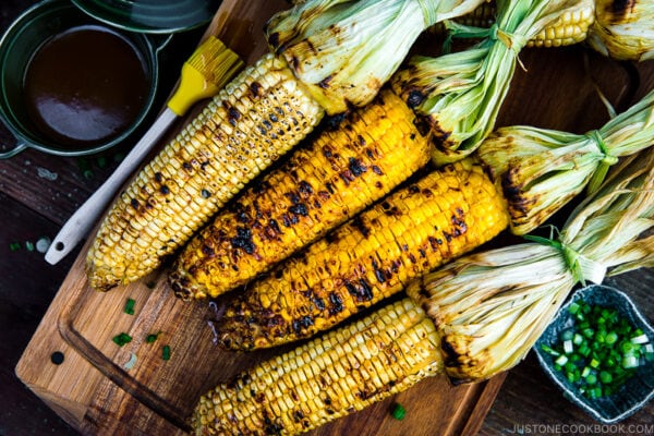 Grilled corn with miso butter sauce on the wooden cutting board.