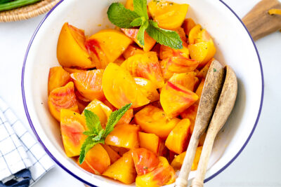 A white enamel bowl containing Heirloom Tomato Salad garnished with mint.