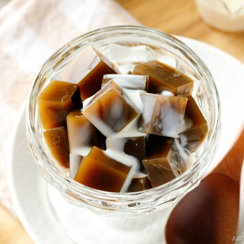 A glass bowl containing cubed Hojicha Jelly drizzled with sweetened condensed milk.