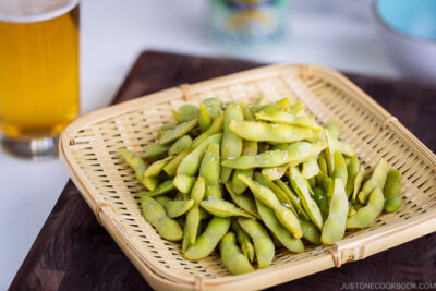 A bamboo basket containing perfectly cooked and salted edamame.