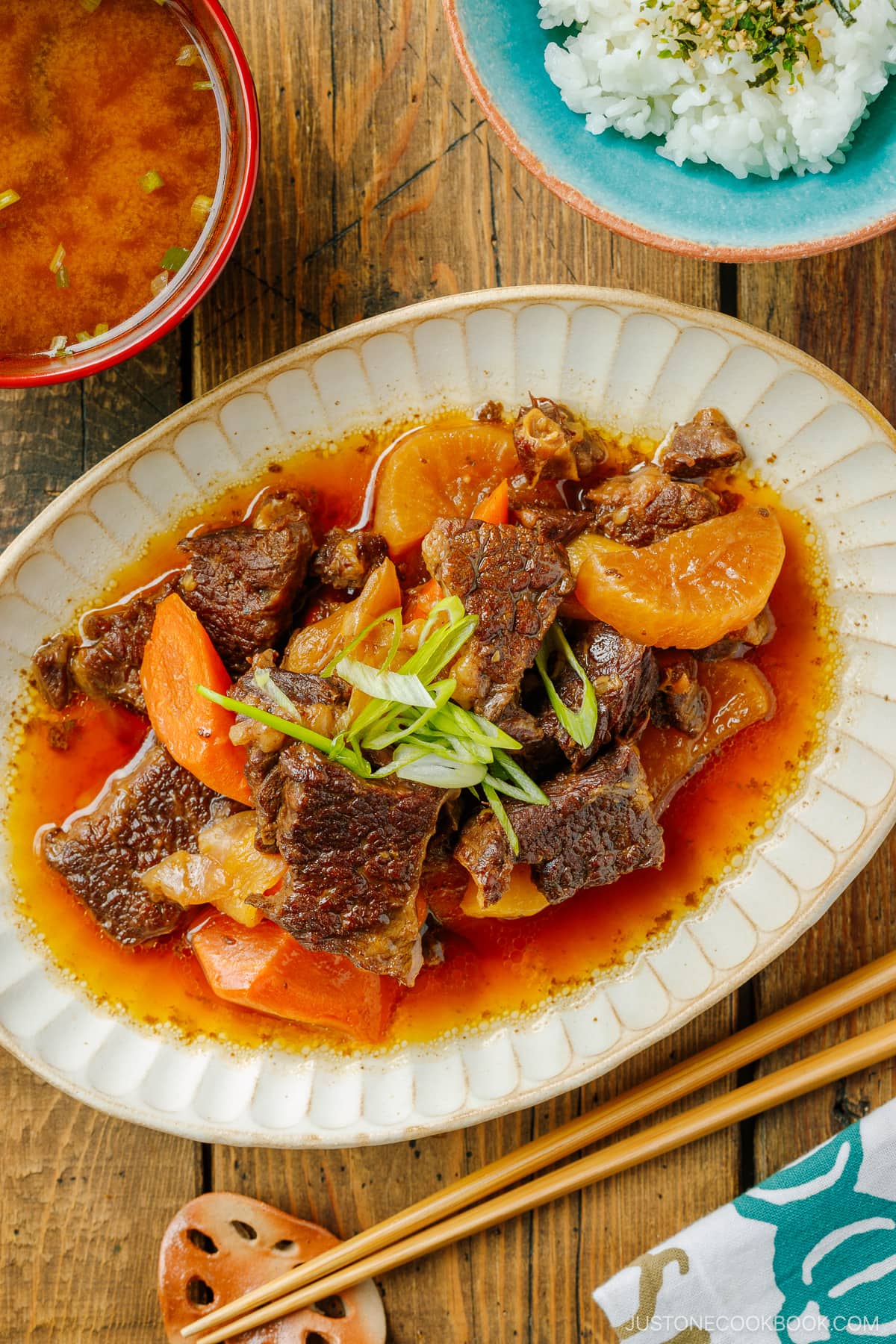 A white ceramic bowl containing Instant Pot Short Ribs with daikon and carrots pressure cooked in a savory sauce.