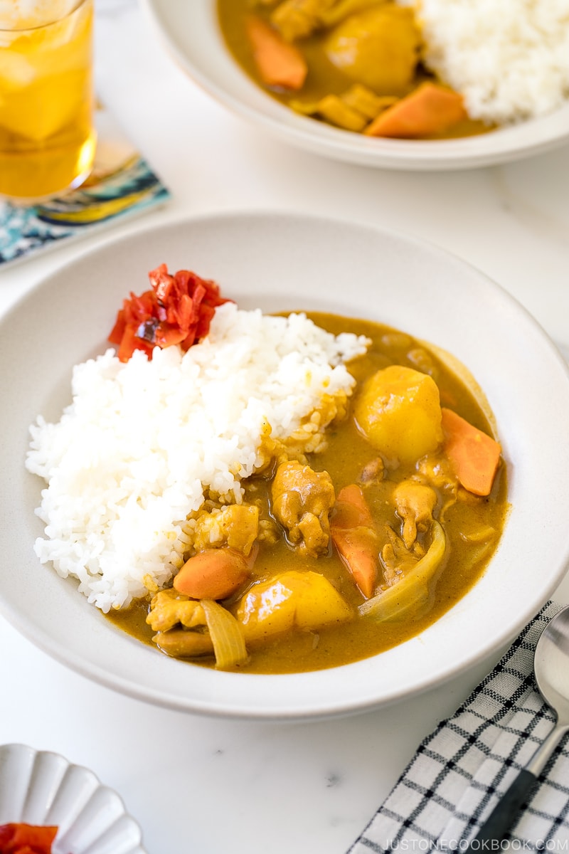 A ceramic bowl containing Japanese Chicken Curry along with steamed rice and fukujinzuke pickles.