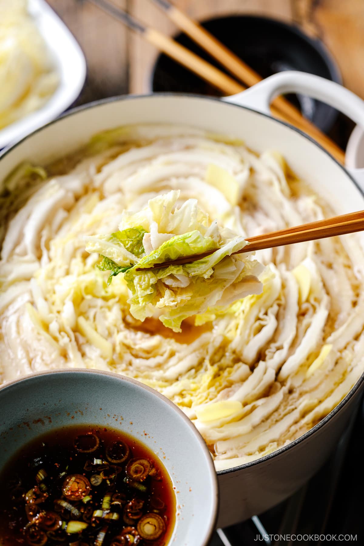 A Le Creuset pot containing Mille-Feuille Nabe, which is a hot pot dish with layers of pork belly slices and napa cabbage slices in a dashi broth.