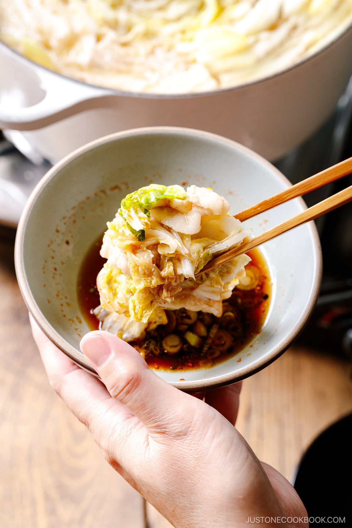 Dipping pork belly slice and napa cabbage in ponzu sauce.