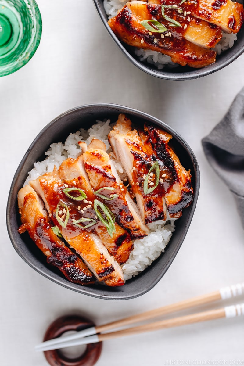 Miso chicken over steamed rice, garnished with sesame seeds and green onion.