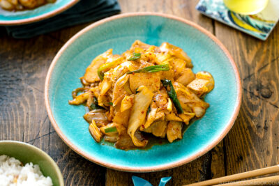 A Japanese ceramic plate containing Pork Kimchi Stir-Fry called Buta Kimchi. It's served with steamed rice.