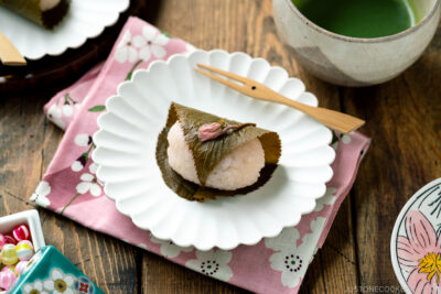 A round fluted plate containing sakura mochi served with matcha tea.