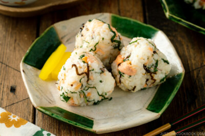 A Japanese ceramic plate containing Salmon and Shio Kombu Onigiri served with daikon pickles.