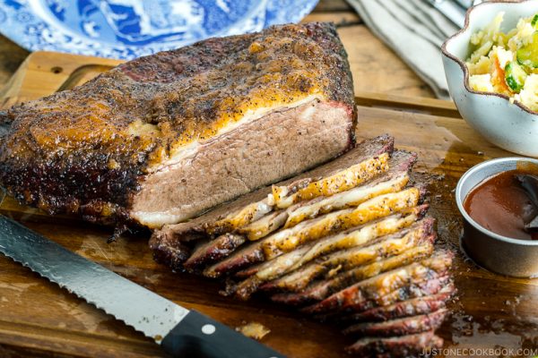 Smoked A5 Japanese wagyu brisket on a wood cutting board next to bbq sauce and potato salad | Easy Japanese Recipes at JustOneCookbook.com