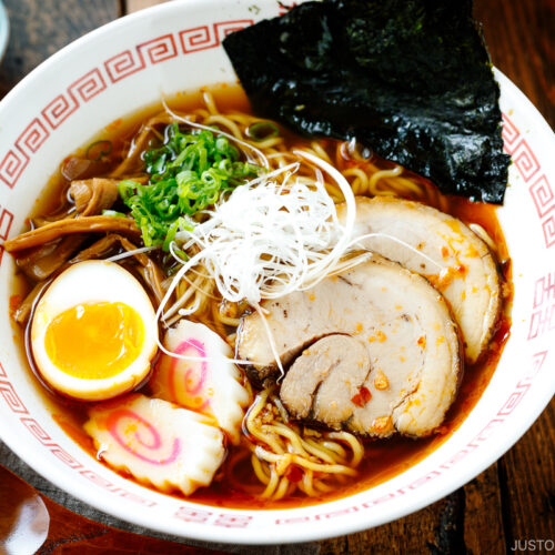 Ramen bowls containing Spicy Shoyu Ramen topped with chashu, marinated egg (ajitama), fish cake, scallions, and nori.