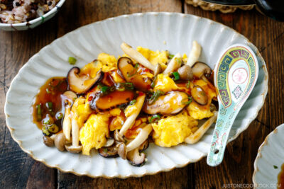 A fluted oval shape containing stir-fried mushrooms and eggs drizzled with ankake sauce.