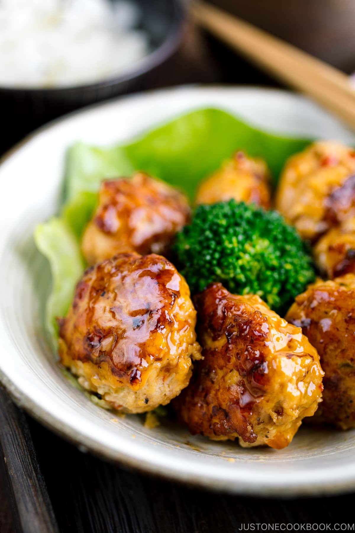 A white bowl containing teriyaki chicken meatballs and broccoli.