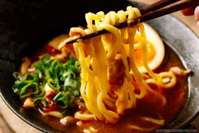 Bowls of Tsukemen dipping soup broth and a plate of ramen noodles and toppings.