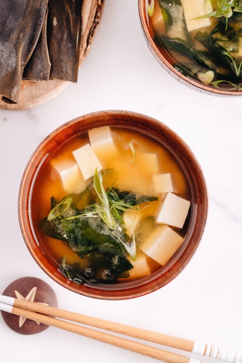 Japanese wooden bowls containing vegan miso soup with tofu and seaweed.