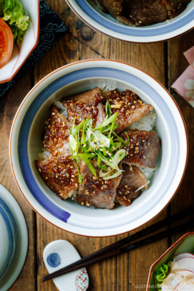 A Japanese donburi bowl containing Yakiniku Don, where pan-grilled well-marbled beef is coated with Japanese BBQ sauce and served over a bed of steamed rice.