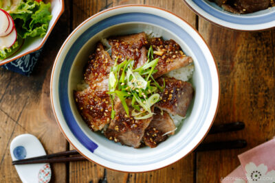 A Japanese donburi bowl containing Yakiniku Don, where pan-grilled well-marbled beef is coated with Japanese BBQ sauce and served over a bed of steamed rice.