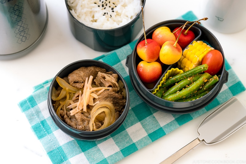 A Zojirushi lunch jar containing steamed rice, gyudon, fruits, and green bean gomaae.